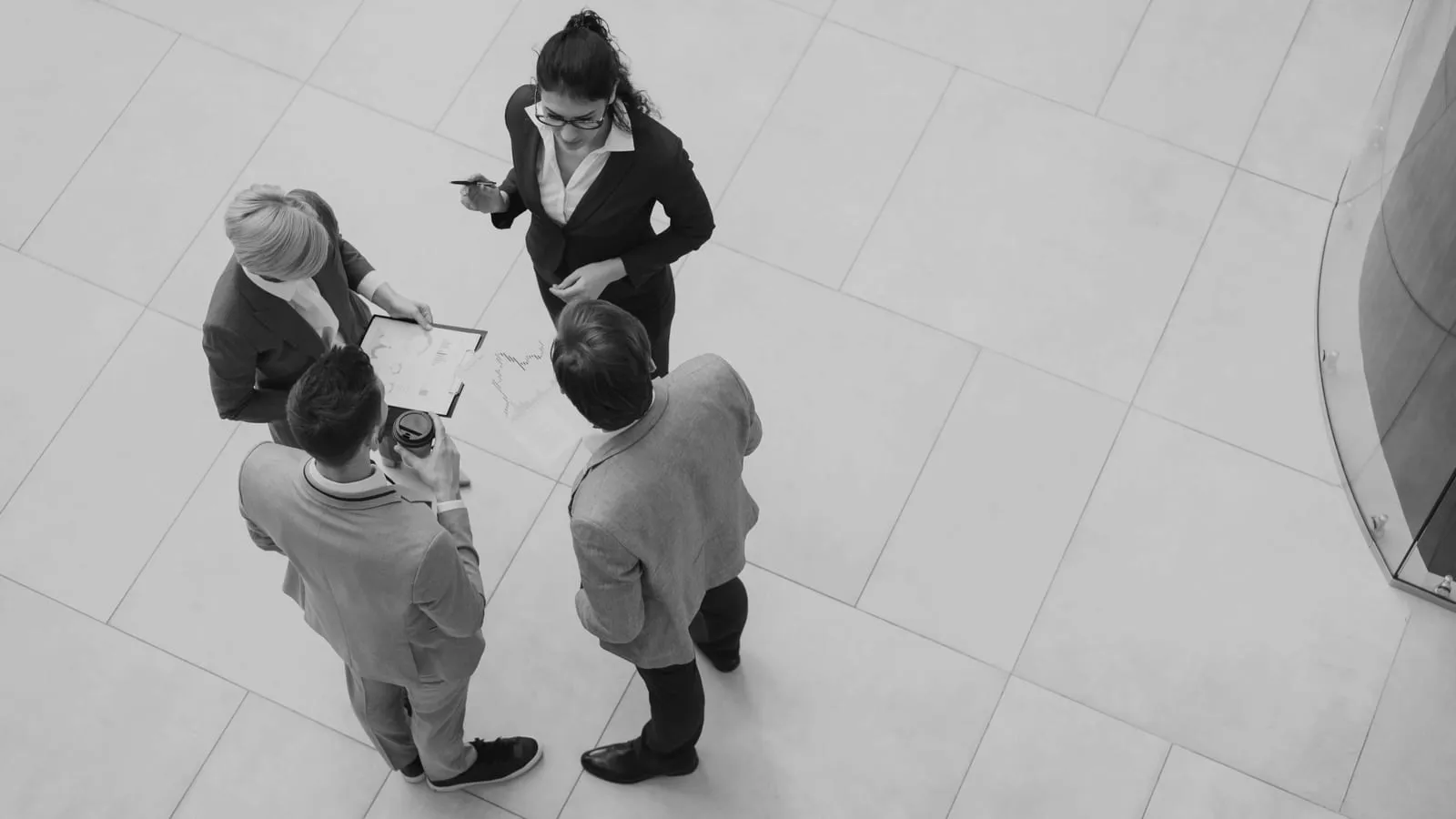 Four colleagues discussing a deal standing in a lobby, seen from above